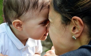 A woman and her baby boy facing each other forehead to forehead 