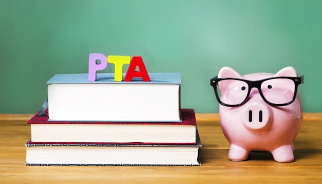 A PTA sign placed on three books next to a piggy bank on a table top