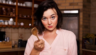 A stay-at-home mom holding a wooden spoon in the kitchen