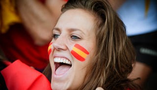 A woman cheerleading at the football game in a red shirt with her mouth open while cheering on