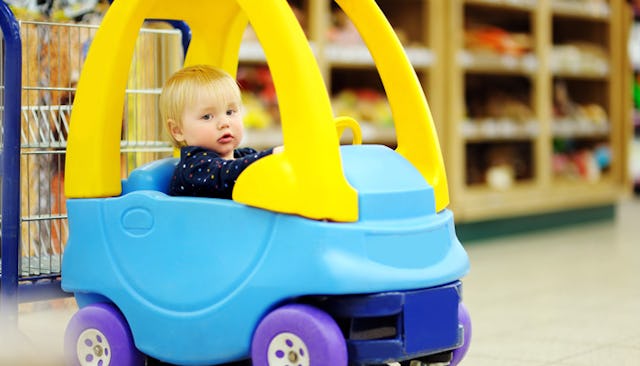 Small boy driving a kid car shopping cart in blue and yellow