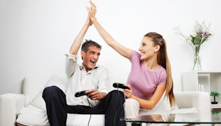 A married couple high fiving while playing a PlayStation.