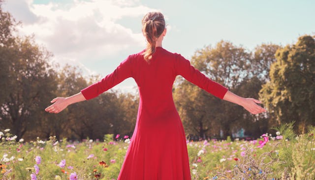 A blonde woman in a red dress with her arms wide open who loves herself