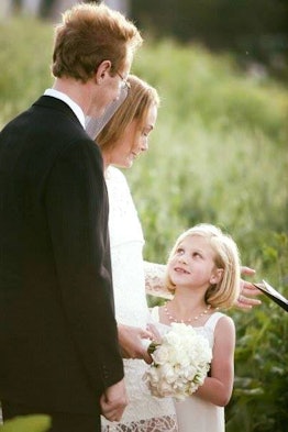 A bride, a groom and a little girl smiling and posing