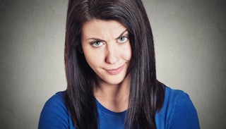 A woman in a blue shirt looking with one raised eyebrow, giving someone a stink eye 