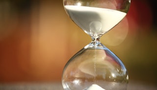 An hourglass with white sand flowing down