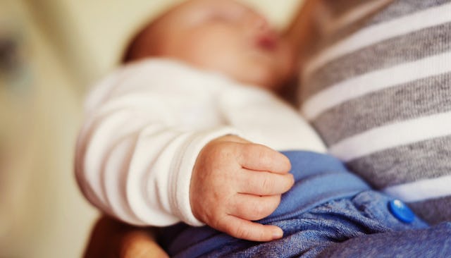 A small baby sleeping in the hands of her mother who has a love/hate relationship with the child's u...