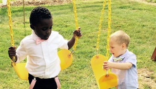 Two boys, with different races, playing together on two swings