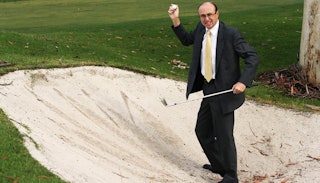 A man playing golf dressed in a suit