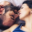A man and a woman facing each other upside down in bed almost kissing