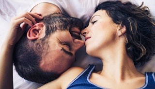 A man and a woman facing each other upside down in bed almost kissing