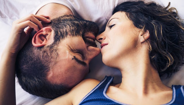 A man and a woman facing each other upside down in bed