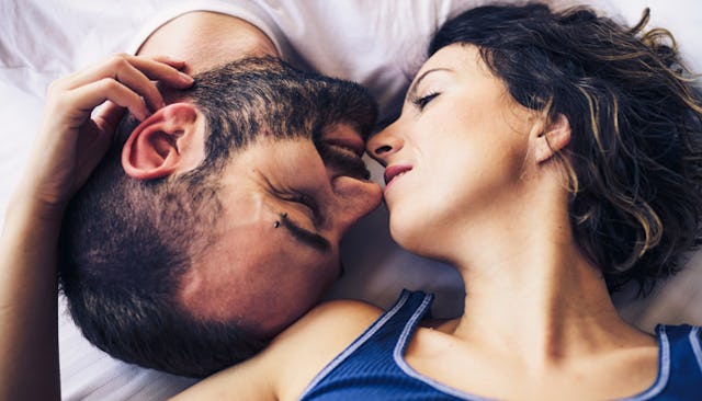 A man and a woman facing each other upside down in bed 