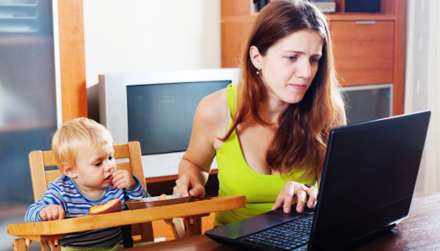 A woman feeding her child while simultaneously working on her laptop 
