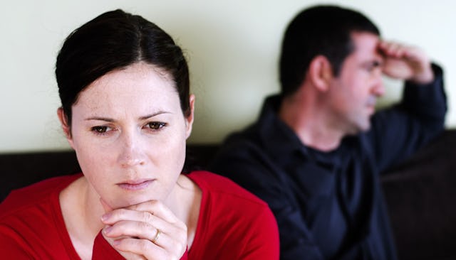 A concerned wife sitting beside her husband, who rests his hand on his forehead.