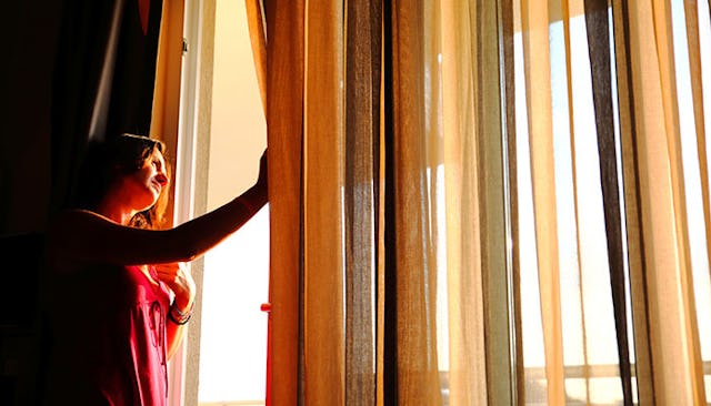 woman-pulling-back-curtain
