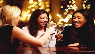 Three women on the girls' night out giving cheers with their glasses 