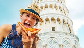 woman-eating-pizza-in-front-of-tower-pisa