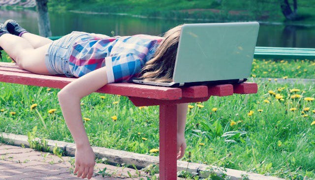 A teenager wearing a blue and red striped shirt and blue shorts sleeping on a bench with her head on...