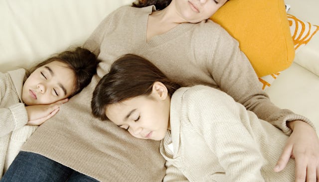 A mom hugging her two kids while they sleep