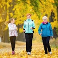 Elder woman jogging with her daughter and granddaughter in a beautiful yellow forest.