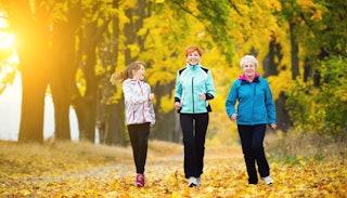 Elder woman jogging with her daughter and granddaughter in a beautiful yellow forest.