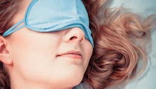 A brunette mom with a blue eye mask taking a nap