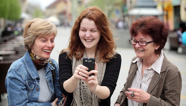 A red-haired younger woman taking a selfie with her two aunts