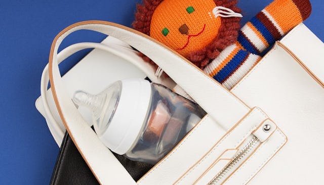 A mom's white bag with a milk bottle and a plush toy lion in it