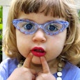 A little girl in a blue shirt, with blue eyes and blue semi-translucent sunglasses with her pointer ...
