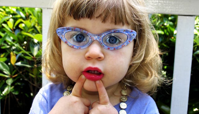 A little girl in a blue shirt, with blue eyes and blue semi-translucent sunglasses with her pointer ...