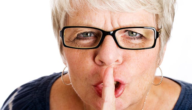An older woman using her finger to shush her kid