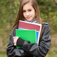 A sixteen-year-old girl holding her school notebooks in green, blue and brown color