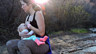 A mother in sportswear breastfeeding her baby outside 