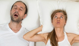 A wife nervously lying down in bed and hating her husband because of his snoring