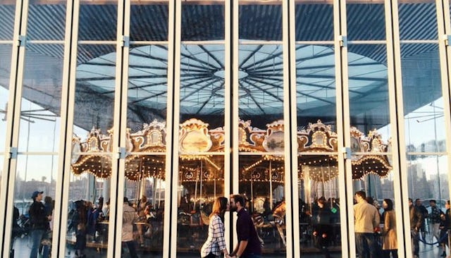 A couple on date night kissing next to a carousel