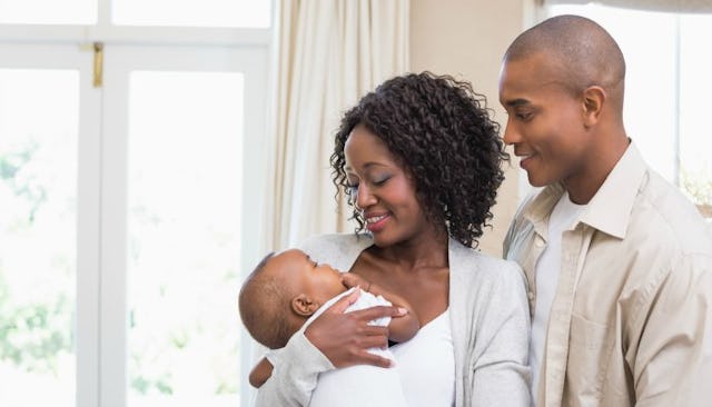A couple in cream and white clothes alone at home with their newborn baby