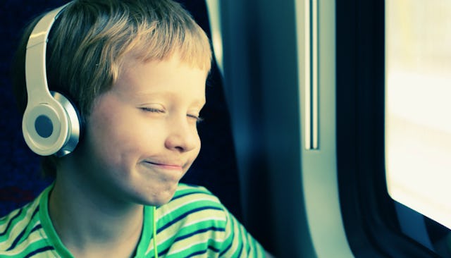 A blonde-haired boy with autism listening to music through his headphones in the car