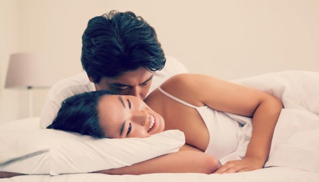 A woman and a man in a bed smiling and sniggling together