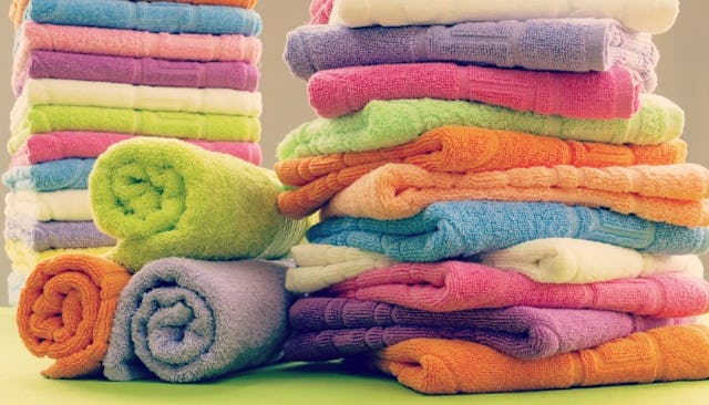 Two stacks of multi-colored towels and three towels rolled up
