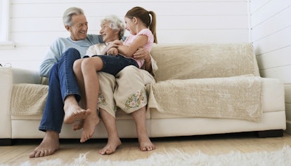 An older man sitting on a beige couch next to an older woman who is holding a little girl in her lap