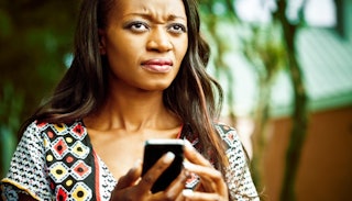 A woman holding her phone, thinking about how she forgot to RSVP to a birthday party