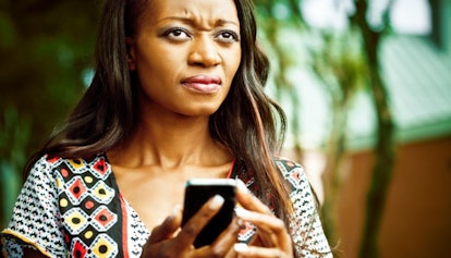 A woman holding her phone, thinking about how she forgot to RSVP to a birthday party 