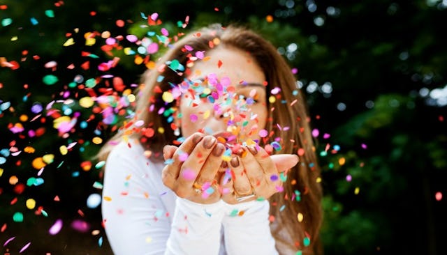 A woman blowing in her hands full of confetti, celebrating the small victories any mom can appreciat...