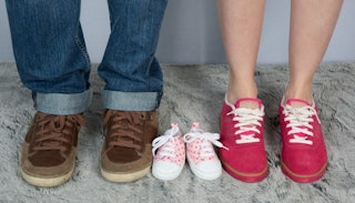 A couple wearing shoes with a toddler’s shoes in between them