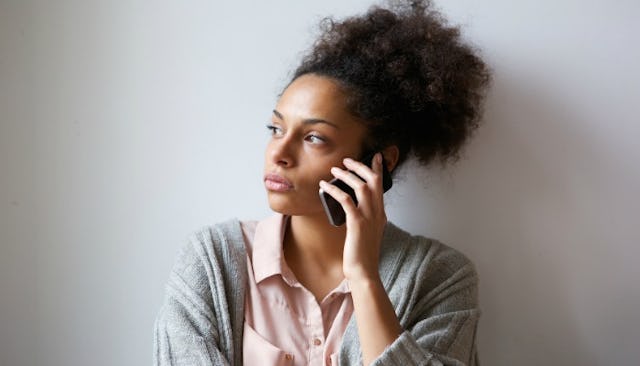 Worried woman leaned against the wall talks on the phone considering divorce