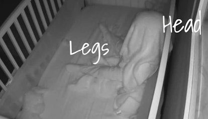 An image from a baby monitor of a child sleeping upside down in the dark