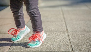 Feet of a young child in light green sneakers on the street