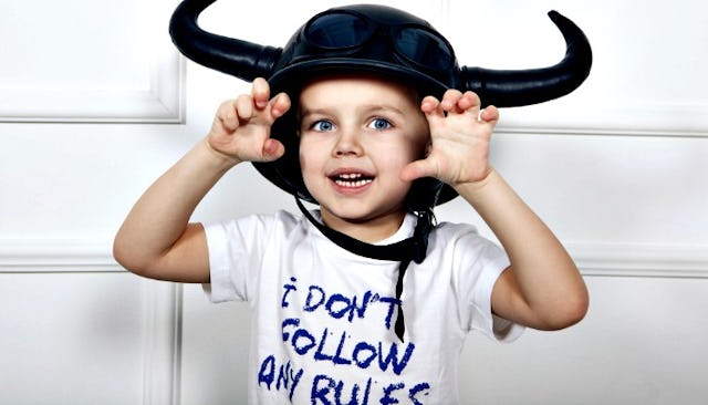 A boy wearing a black helmet with horns and a white T-shirt reading: ' I don't follow any rules.'