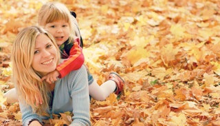 A mother playing with her daughter in a pile of leaves